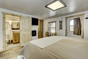 A bedroom with a bed, a wooden wardrobe, a bathroom with a toilet, and a window with blinds.