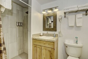 A bathroom with a shower, a sink with a mirror, and a toilet.