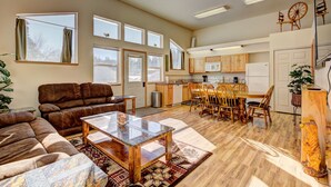 A spacious living room with a sofa, a coffee table, and a dining area with chairs and a table. - Cascade Lake Inn (Cascade)