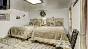 A bedroom with two beds, a ceiling light, a wall-mounted air conditioner, and a window with blinds. - Cascade Lake Inn (Cascade)