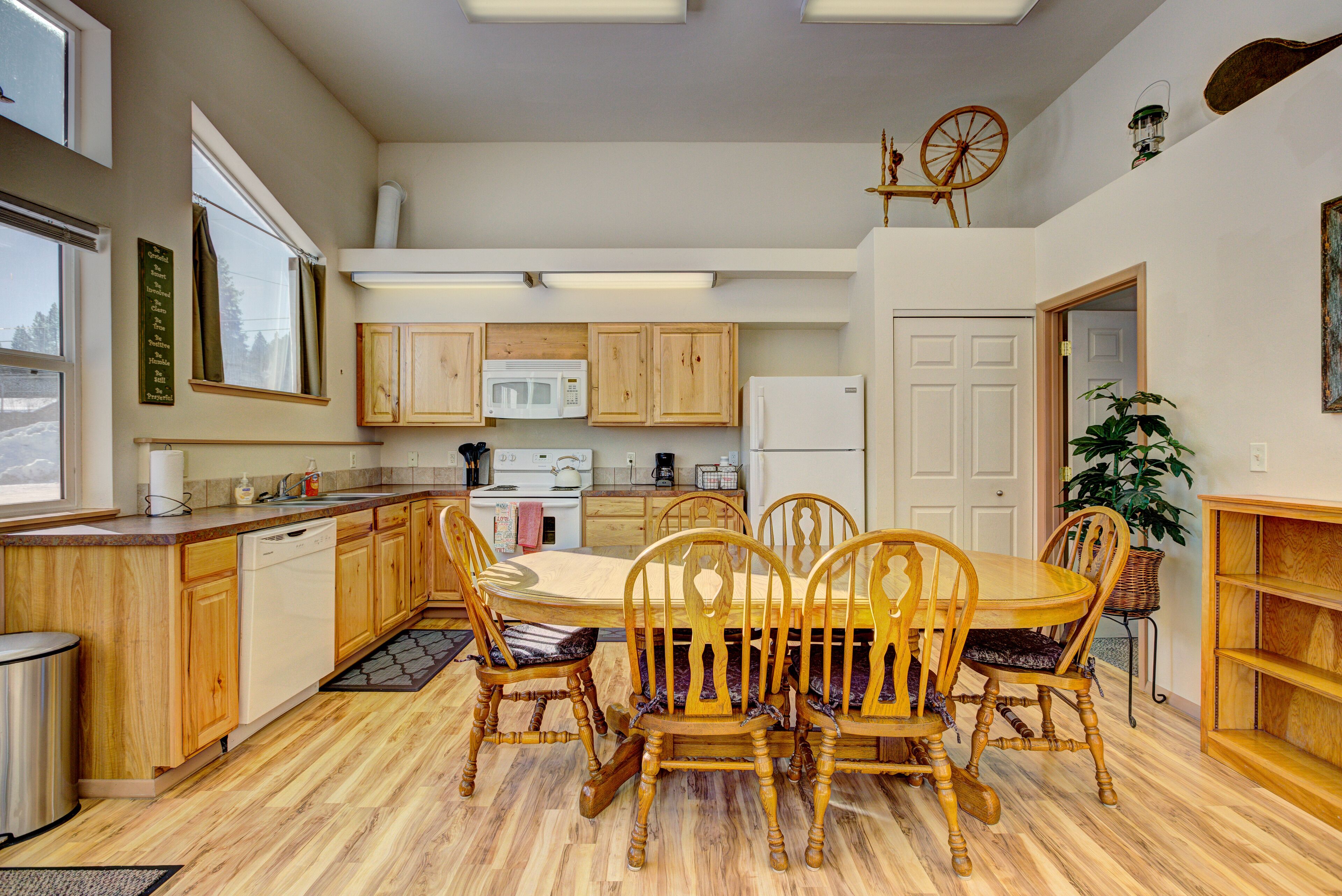 A kitchen with wooden cabinets, a white refrigerator, a microwave, and a dining table with chairs.
