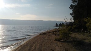 A beach with a sandy shore, a fallen tree, and a calm body of water. - Cascade Lake Inn (Cascade)