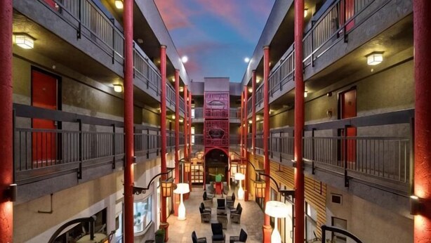 A hotel atrium with multiple floors, a central staircase, and outdoor seating areas. - Best Western Plus Dragon Gate Inn (Los Angeles)