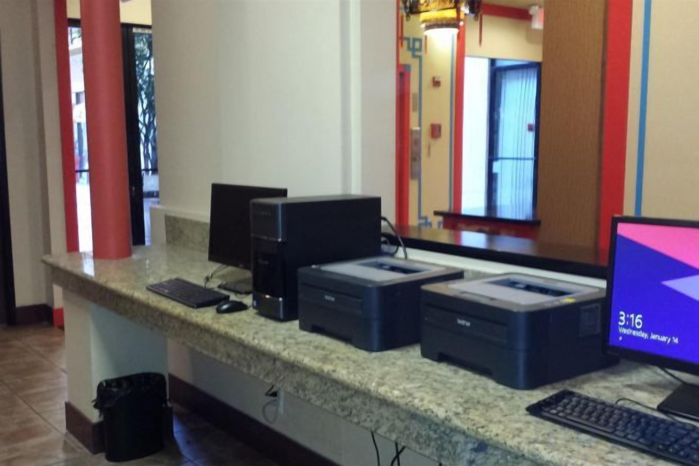 A reception desk with a computer, printer, and keyboard.