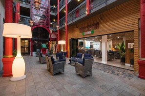 An indoor atrium with wicker furniture, a staircase, and a restaurant with a visible menu. - Best Western Plus Dragon Gate Inn (Los Angeles)