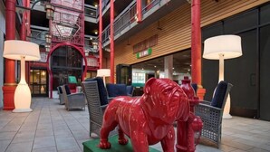 A red bull statue on a green platform in a lobby with seating and lamps. - Best Western Plus Dragon Gate Inn (Los Angeles)
