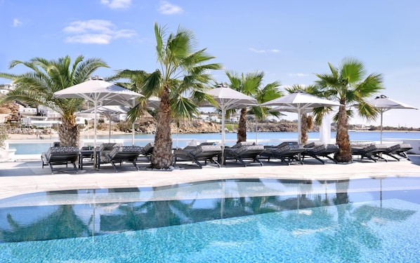 Relax by the serene pool surrounded by palm trees and a stunning coastline view.