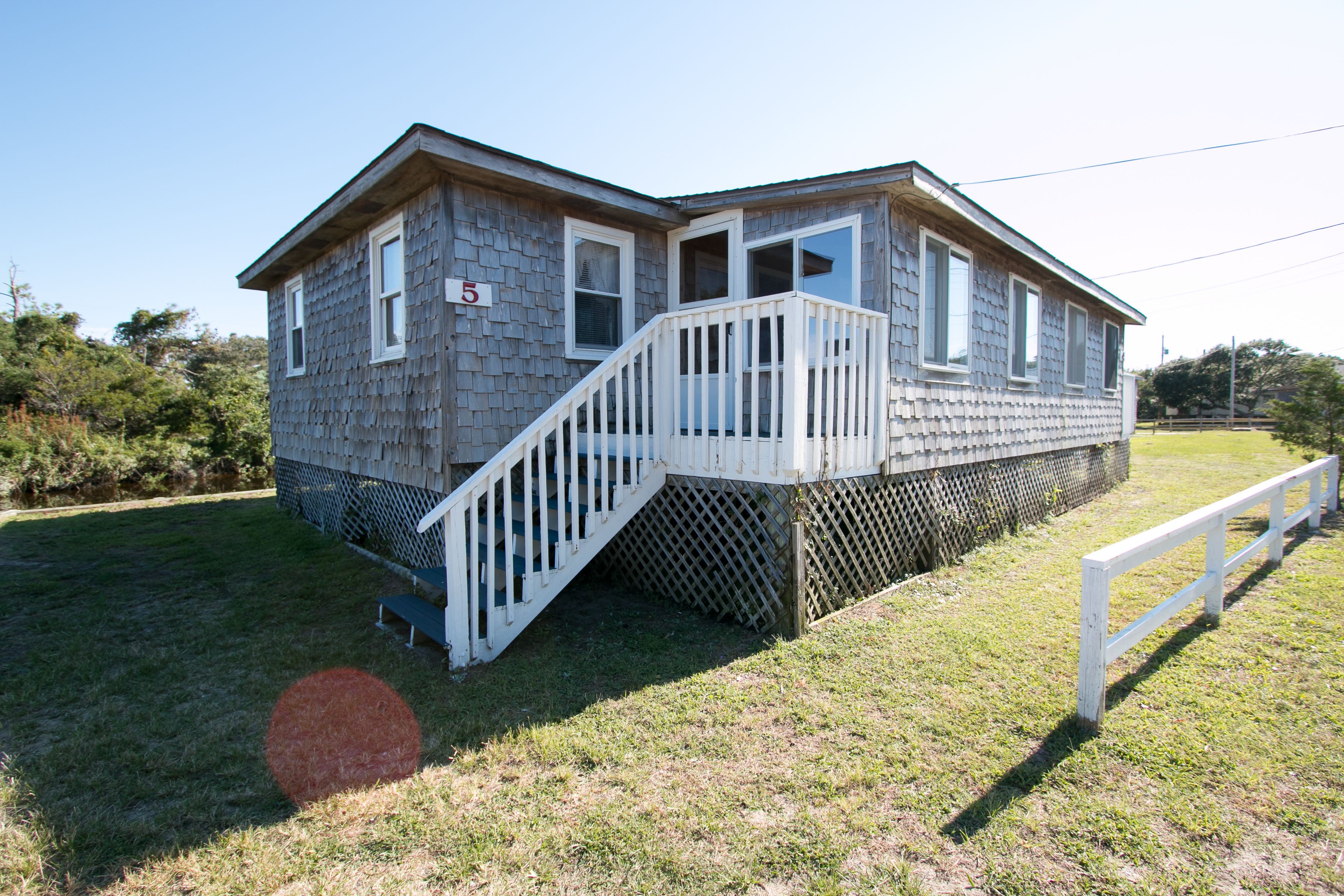 A two-story house with a porch and a number "5" sign.