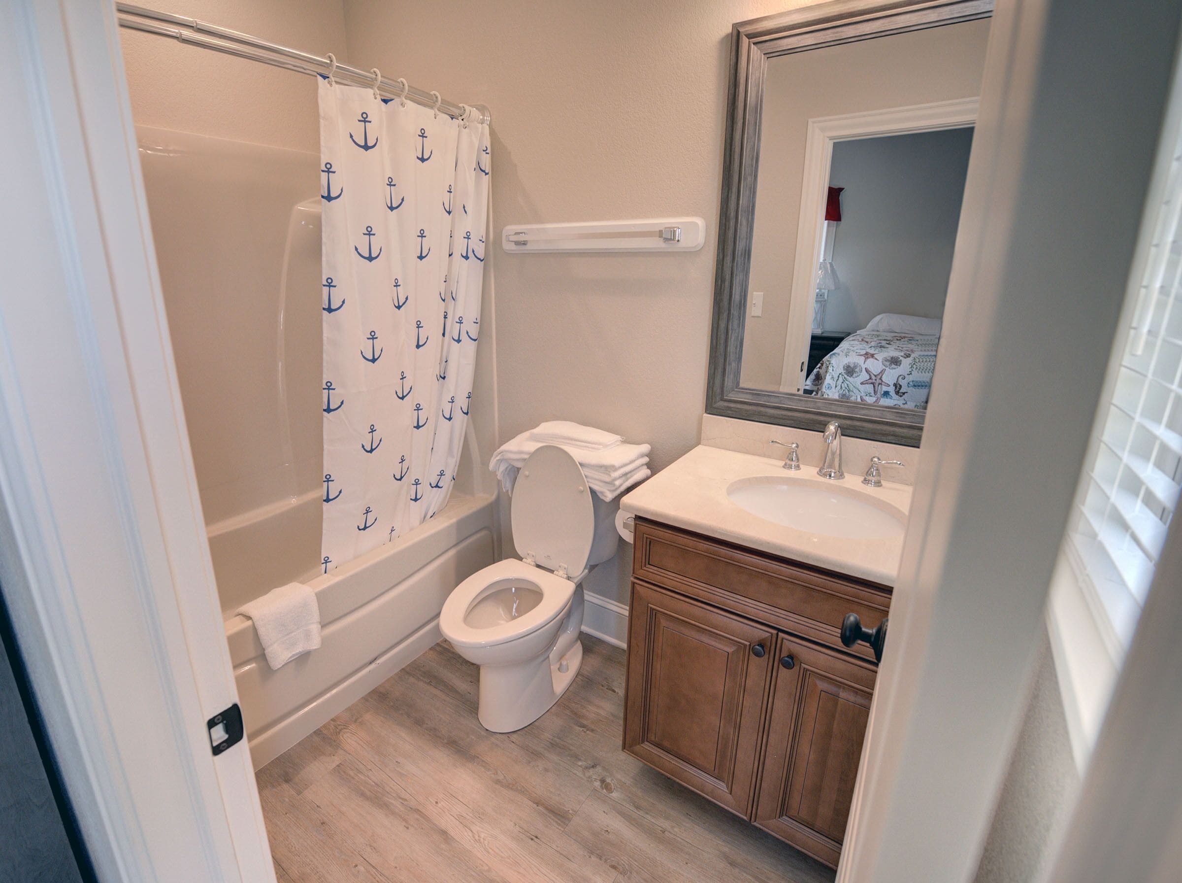 A bathroom with a bathtub, toilet, and vanity with a mirror.