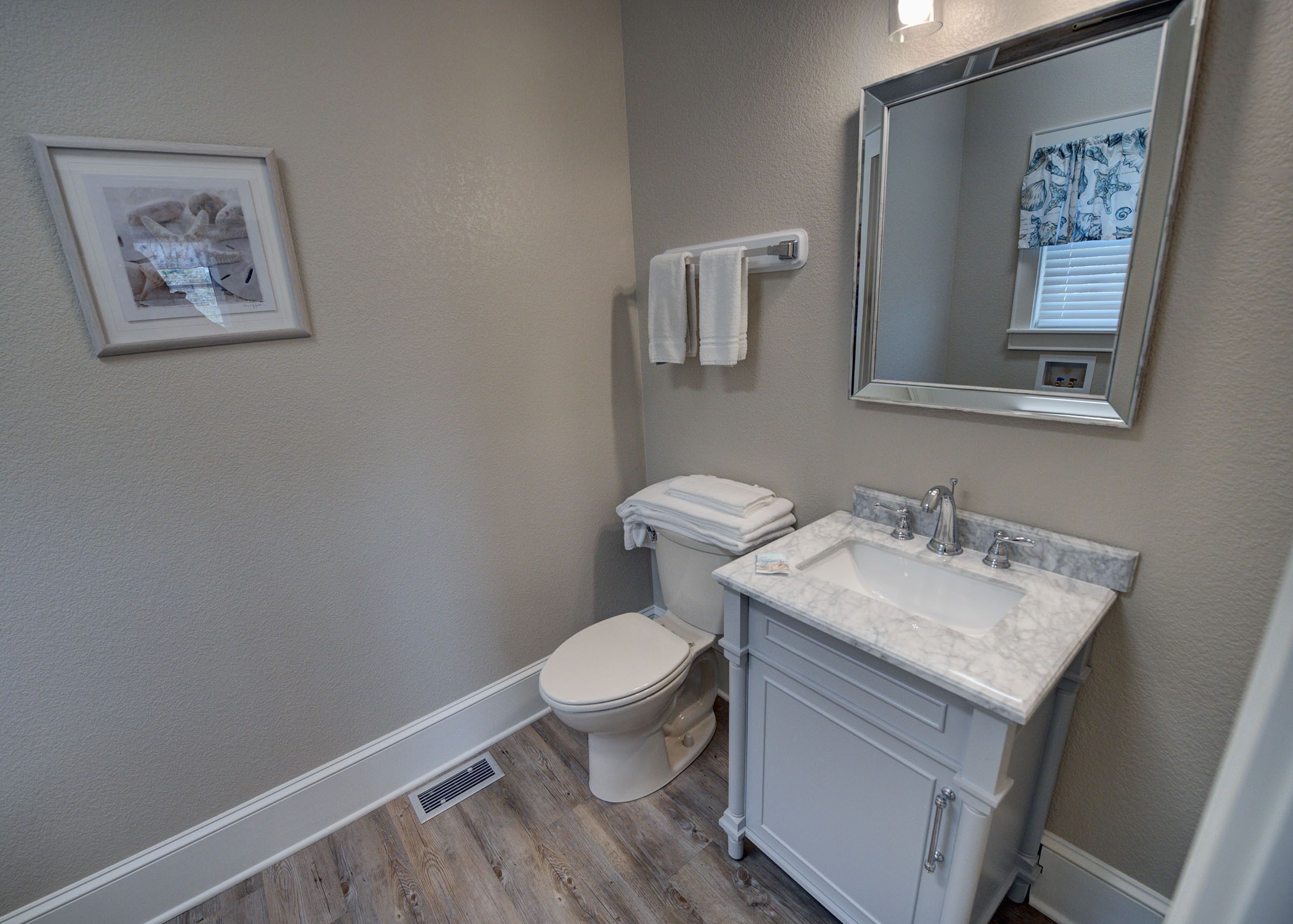 A bathroom with a toilet, sink, and mirror.