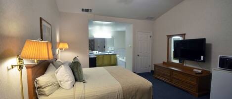 A hotel room with a bed, bedside lamps, a television, a dresser, and a ceiling fan.