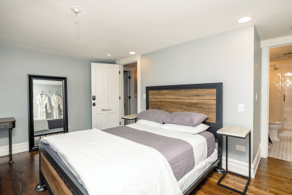 Une chambre à coucher avec un lit, des tables de chevet, un miroir et une porte portant l’inscription « Munro ».