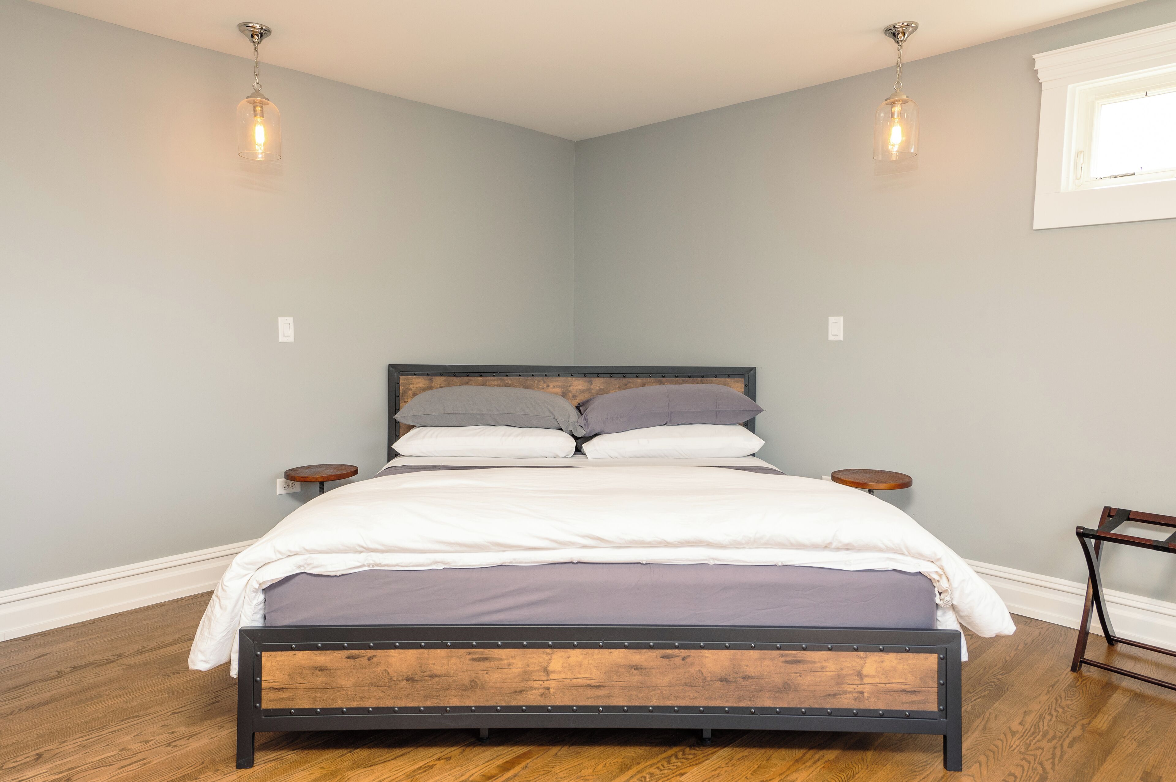 Um quarto com uma cama, duas mesas de cabeceira e um criado-mudo.