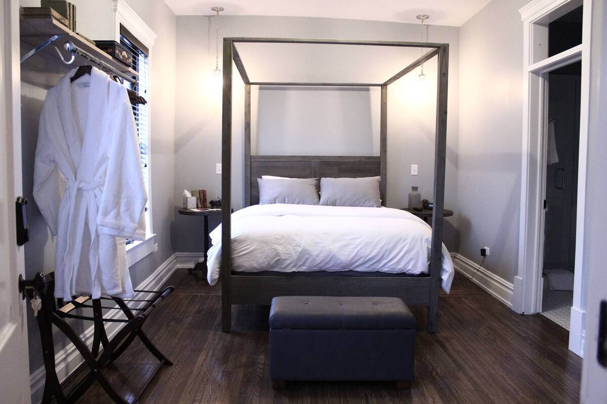 Une chambre moderne avec un lit à baldaquin, un dressing et un plancher en bois.