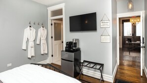 Ett hotellrum med en säng, ett kylskåp, en kaffebryggare och en tv.