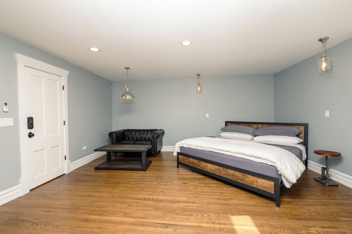 Une chambre à coucher avec un lit, un canapé en cuir, une petite table et une porte.