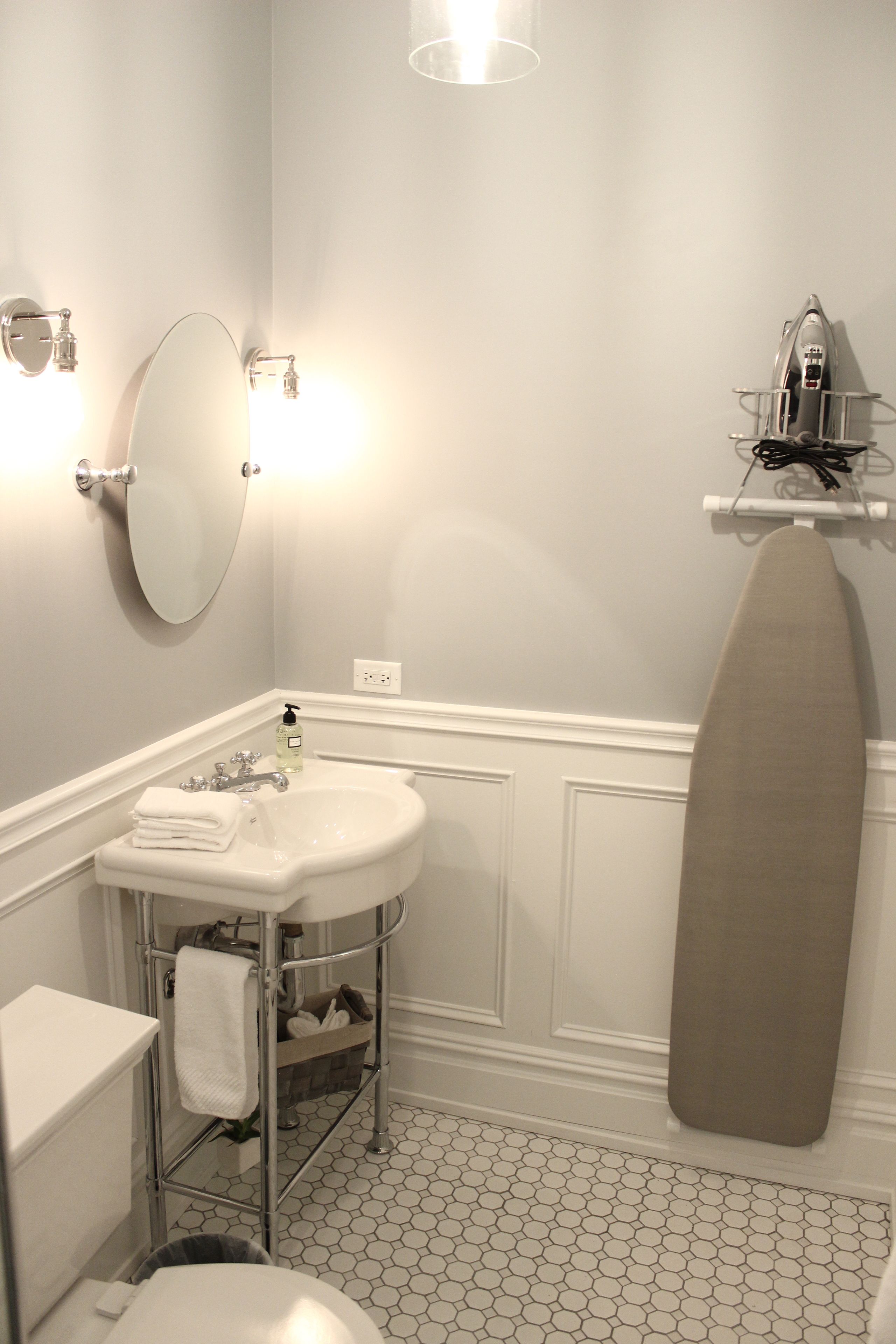 A bathroom with a sink, mirror, and ironing board.