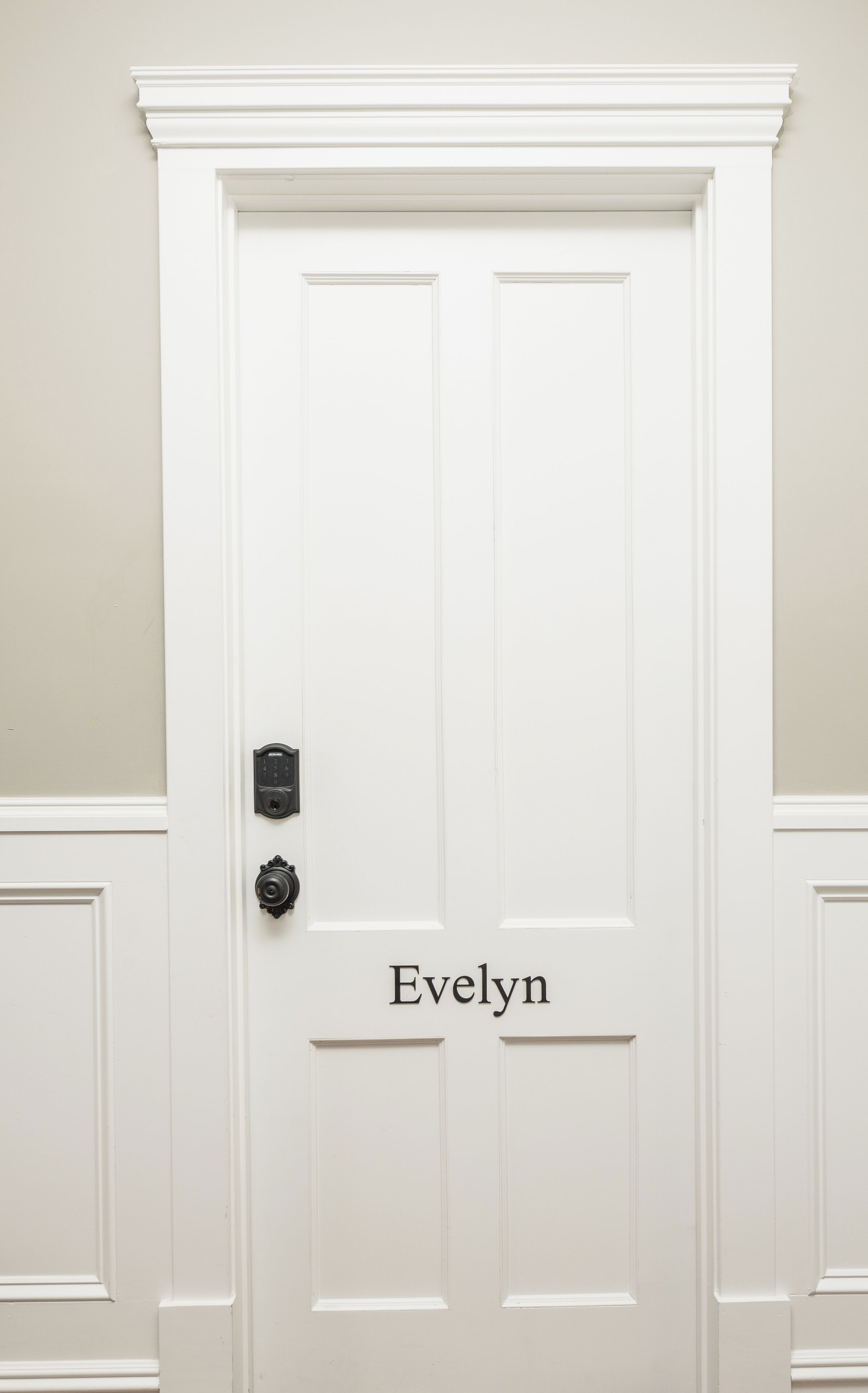 Une porte blanche avec une plaque portant le nom « Evelyn » et un bouton de sonnette.