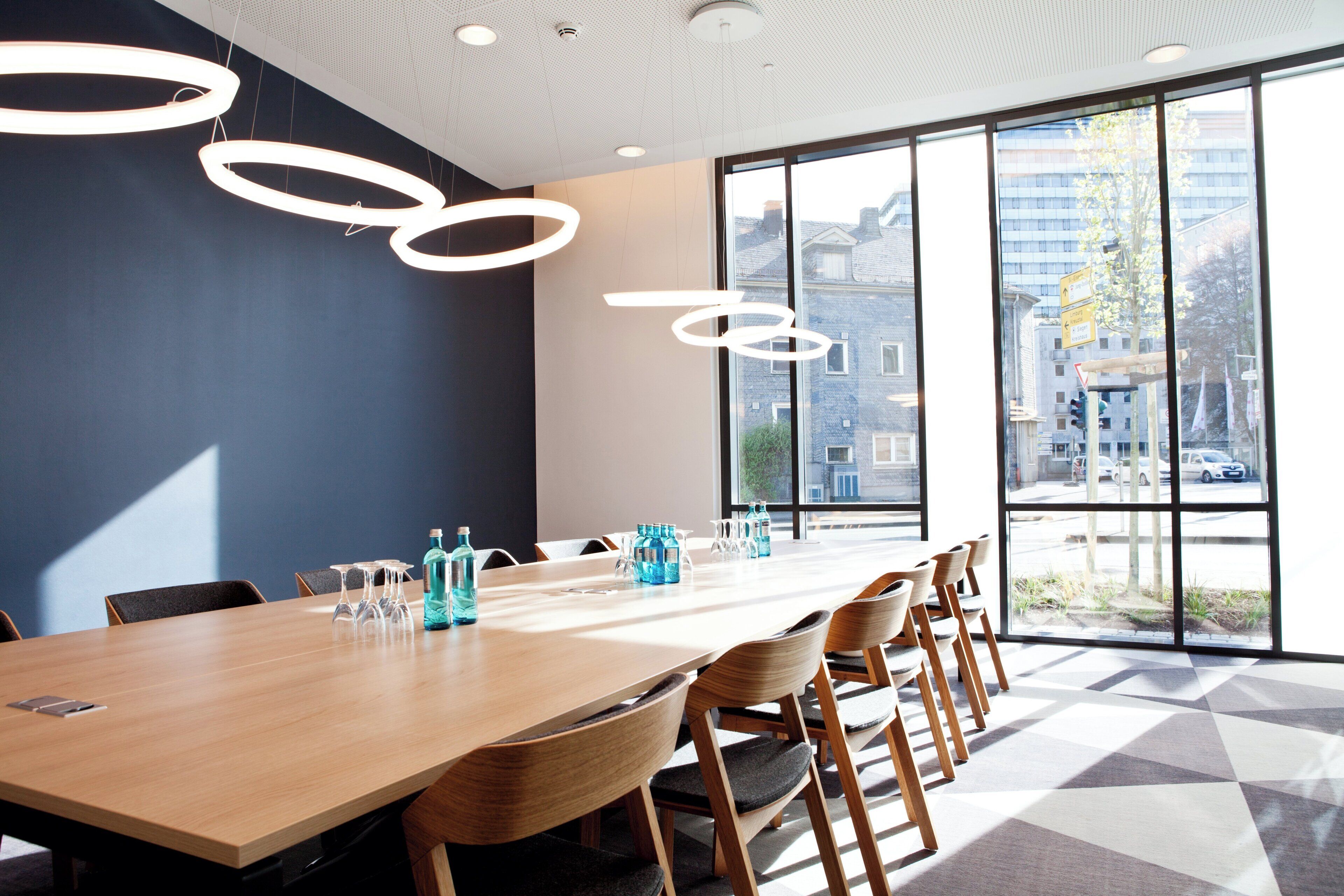 A conference room with a long table, chairs, and hanging light fixtures.