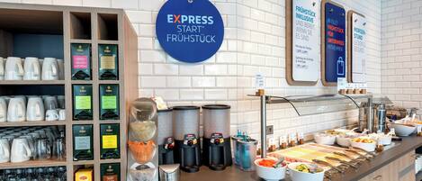 A breakfast buffet area with various food options, a coffee station, and a sign indicating the availability of inclusive breakfast.
