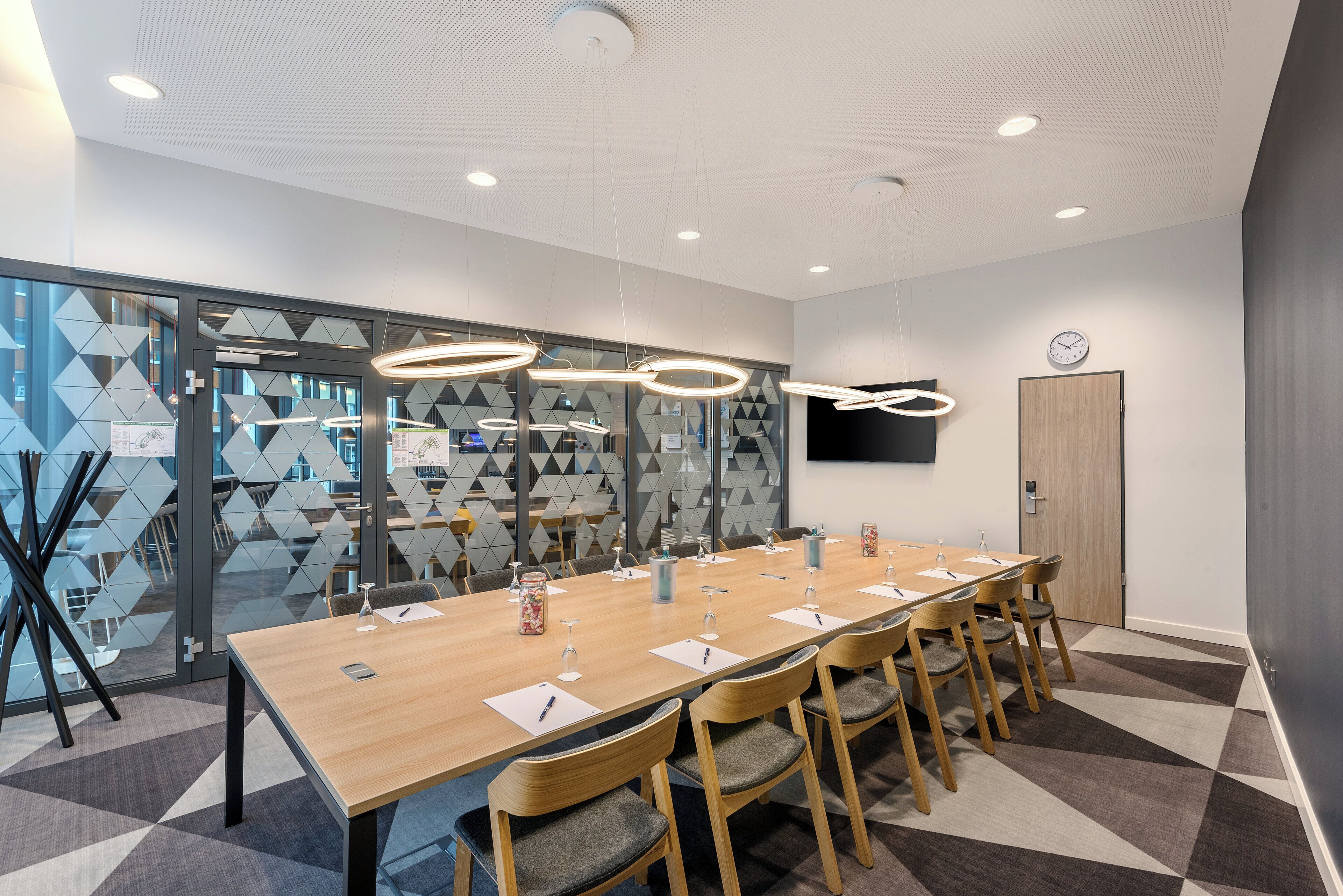 Une salle de conférence avec une longue table, des chaises et une horloge au mur.