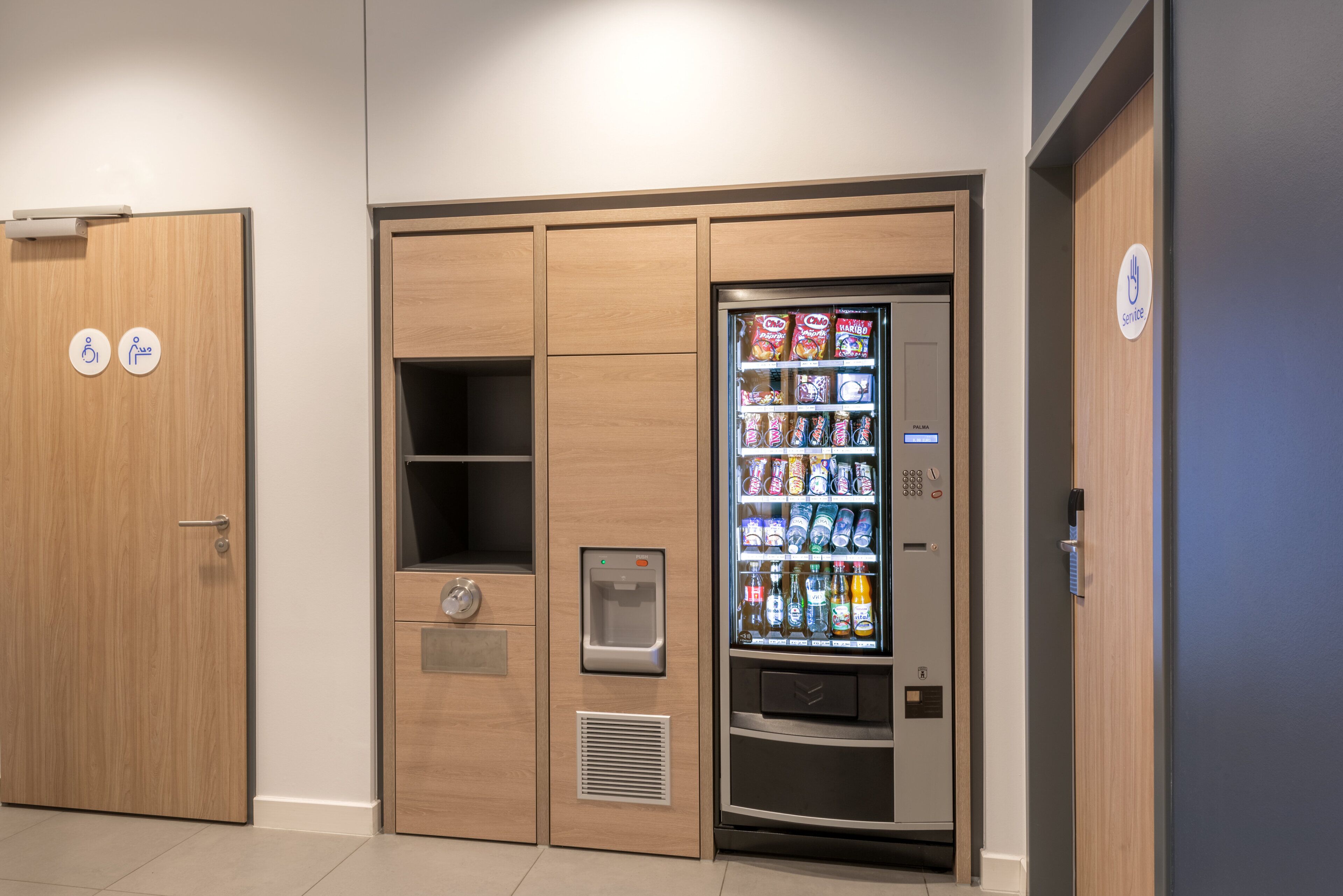 Ein Getränkeautomat mit Snacks und Getränken, ein Wasserspender und ein Druckknopf.