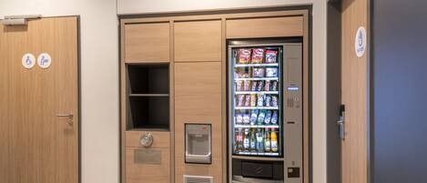 Máquina expendedora con refrigerios y bebidas, dispensador de agua y un botón pulsador.