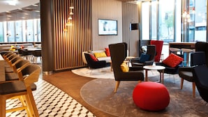 Un área de estar moderna con un gran ventanal, un televisor de pantalla plana y diversas opciones de asientos, incluyendo sofás y sillones.