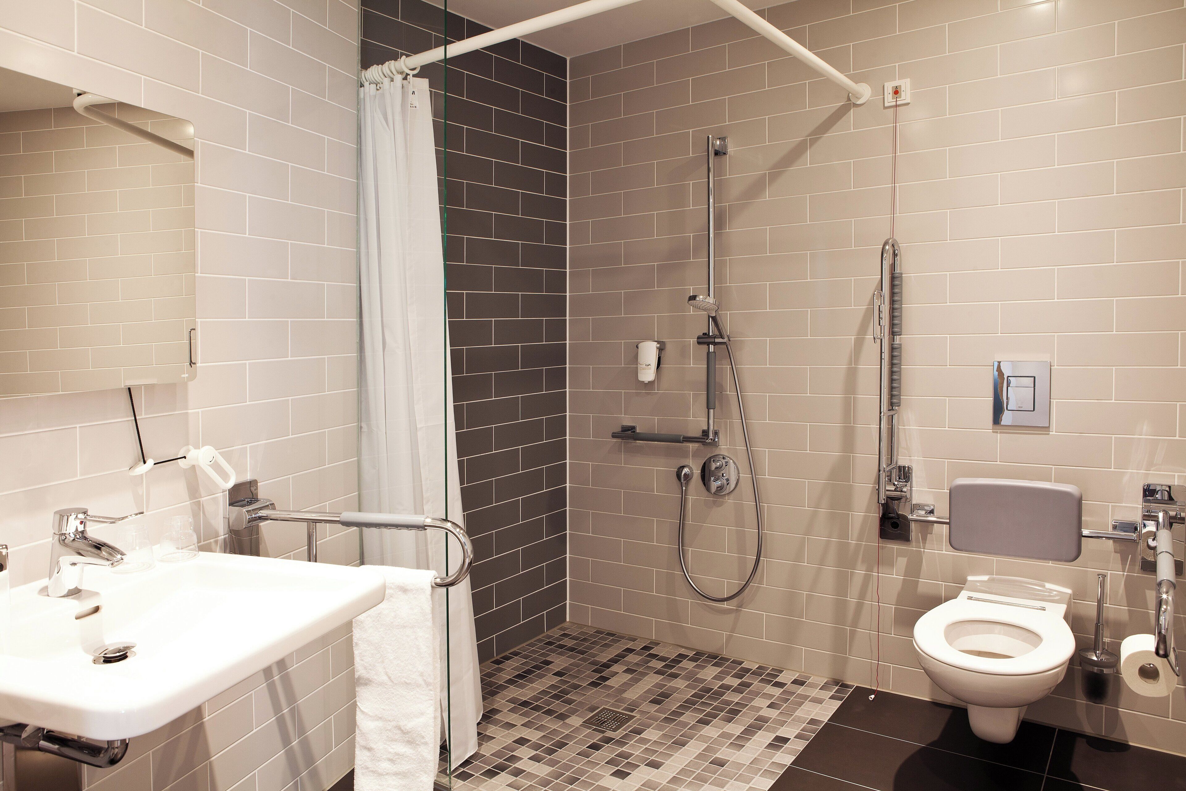 A bathroom with a shower, toilet, sink, and a towel rack.