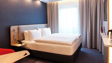A modern hotel room with a large bed, a desk, and a chair.