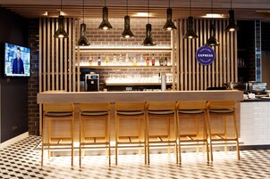 A bar area with wooden bar stools, pendant lighting, and a visible sign for 'EXPRESS Cafe & Bar'.