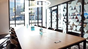 Ein Konferenzraum mit einem langen Tisch, Stühlen und Blick auf die Stadt durch große Fenster.