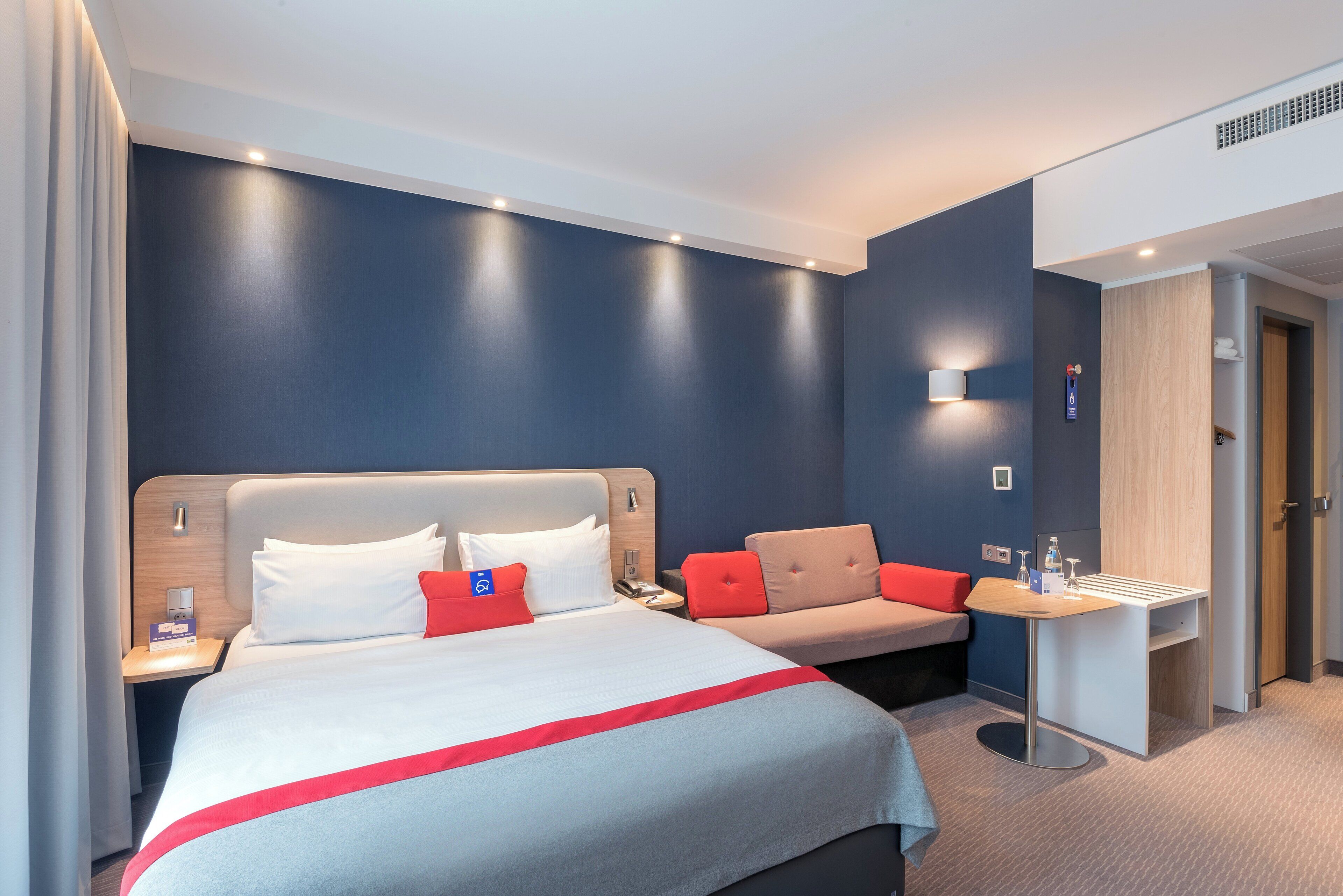 Una habitación de hotel con cama, mesita de noche y un escritorio pequeño con silla.