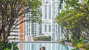 A swimming pool with a person in the water, surrounded by greenery and tall buildings in the background. - Sofitel Singapore City Centre (Singapore)