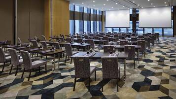 A conference room with tables, chairs, a projector screen, and large windows.