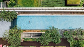 An aerial view of a modern building with a swimming pool, green terraces, and outdoor seating areas.