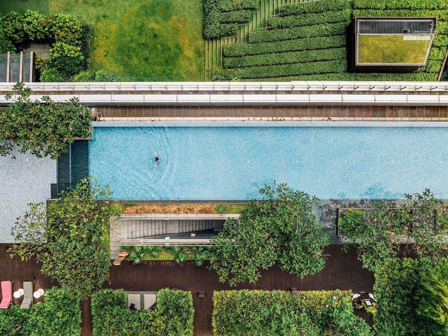 Vista aérea de un edificio moderno con piscina, terrazas verdes y zonas de estar al aire libre.