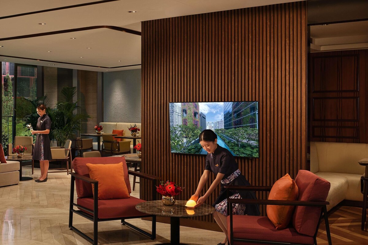 A modern lobby with a large TV, comfortable seating, and a reception area.