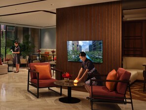 A modern lobby with a large TV, comfortable seating, and a reception area. - Sofitel Singapore City Centre (Singapore)