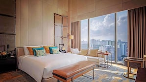 A spacious hotel room with a large bed, a bench, a small table, and a view of the city skyline. - Sofitel Singapore City Centre (Singapore)