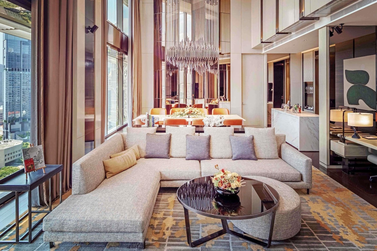 A modern hotel lobby with a large sectional sofa, a round coffee table, and a chandelier.