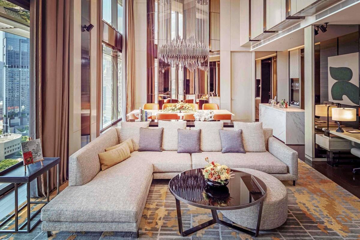 A modern hotel lobby with a large sectional sofa, a round coffee table, and a chandelier.