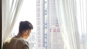 Ein Zimmer mit großem Fenster, einem Bett, einem Sessel und einem Tisch.