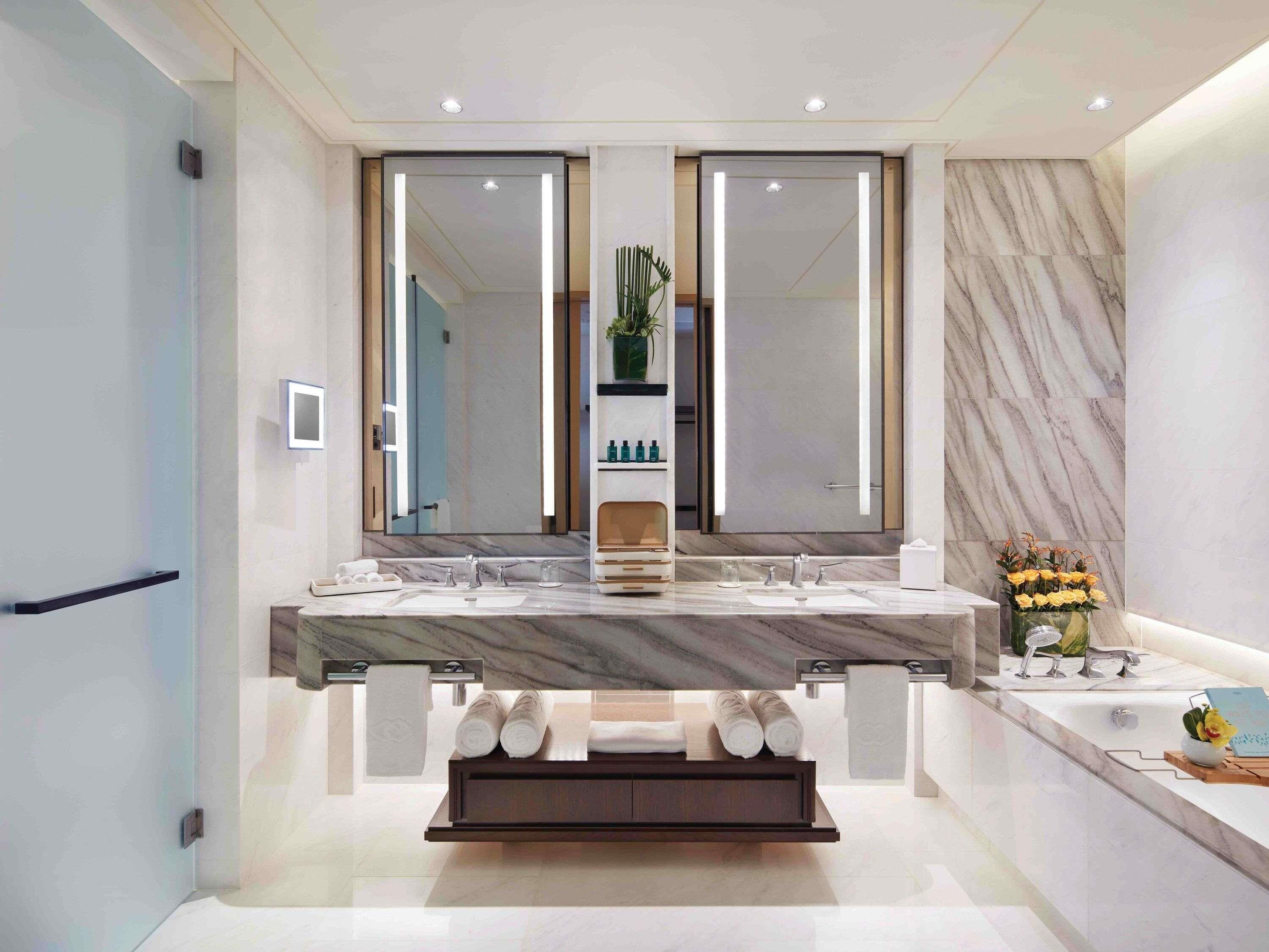 A modern bathroom with a large mirror, dual sinks, a vanity, and a towel rack.