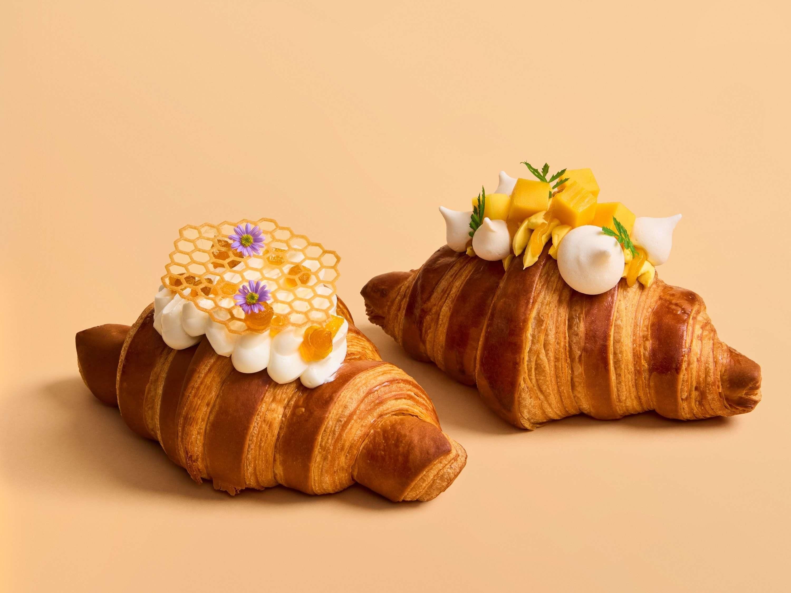 Two croissants with decorative toppings.
