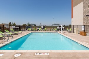 A swimming pool with lounge chairs and a safety sign indicating a depth of 5 feet 0 inches.