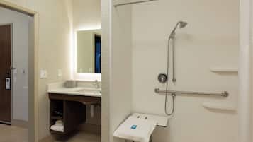 Un baño de hotel con ducha, lavamanos y toallero.