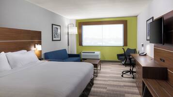 Habitación de hotel con cama, escritorio, silla, televisor y ventana.