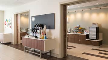 A modern kitchen area with a coffee station, a refrigerator, and a display of fresh fruits and eggs.