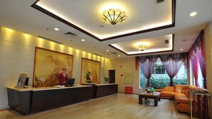 Zona de recepción de hotel con mostrador, sofá y una mesa de centro.